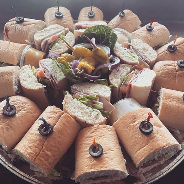 A platter of Your Pizza Stop's submarine sandwiches, garnished with olives and peppers.