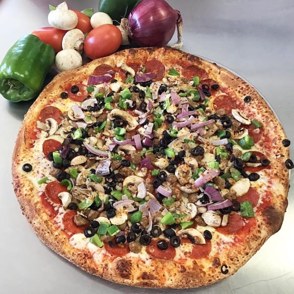 A Your Pizza Stop pizza with pepperoni, sausage, mushrooms, olives, onions, and bell peppers.