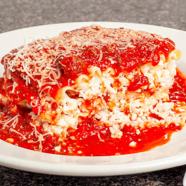 A generous serving of lasagna with rich red sauce and grated cheese on a white plate.